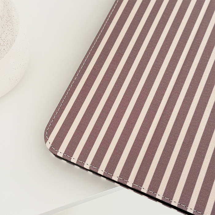 Brown and beige striped iPad case on a white surface next to a round, textured container.
