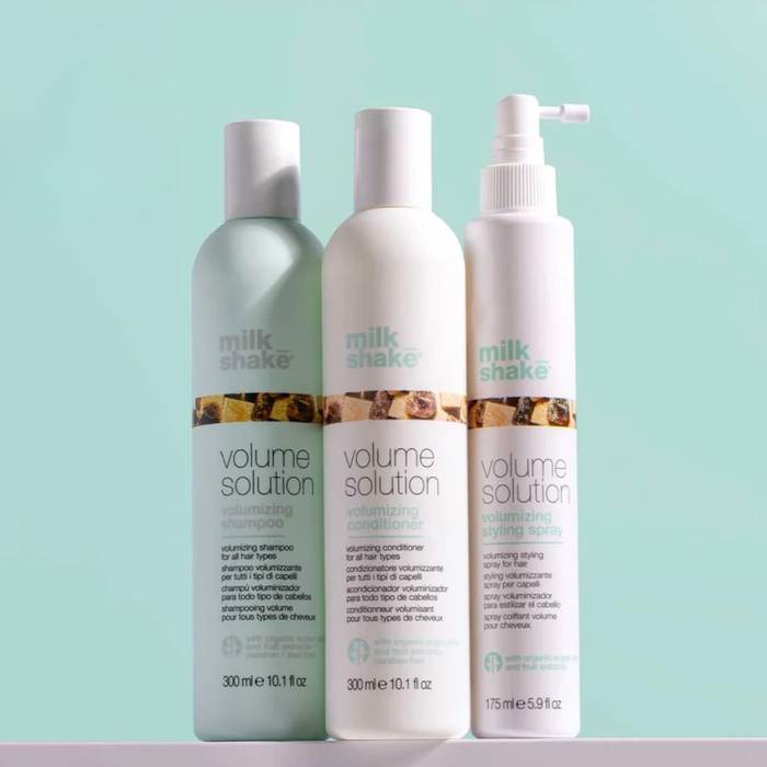 Three bottles of milk_shake Volume Solution hair care products on a light blue background