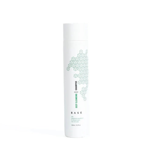 A bottle of Base Deep Cleansing Shampoo with a white and green label design, indicating it is a vegan friendly and paraben free product.