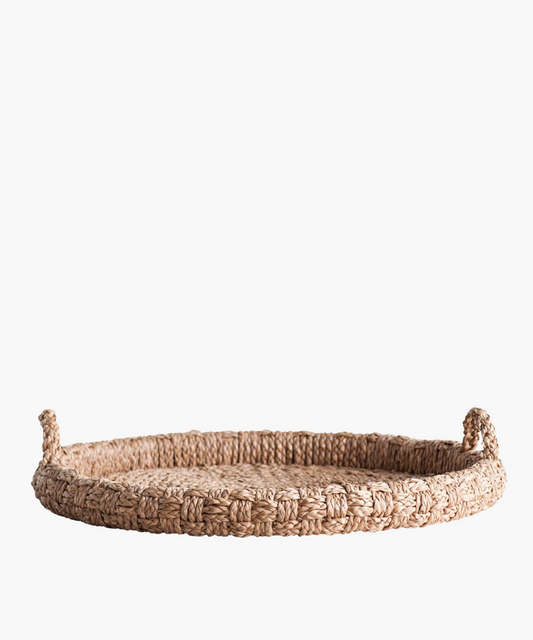 Round braided wicker tray or basket with two looped handles. The natural fibers create a warm, rustic feel. The basket's texture is tightly knit and sturdy. | SW Home