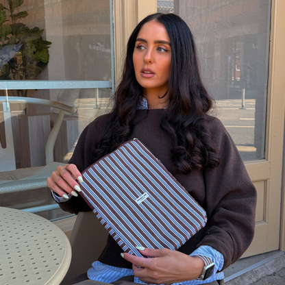 Girl sat outside cafe holding her Brown and Blue Stripe iPad Sleeve