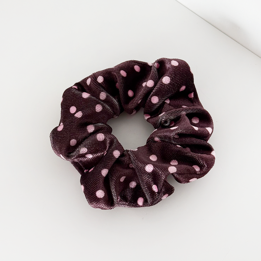 Brown polka dot fabric scrunchie on a white surface.