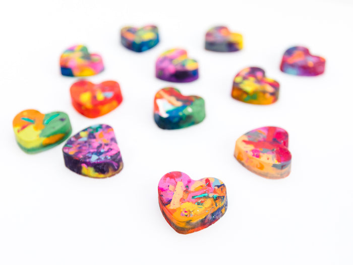 A collection of colorful heart-shaped crayons with a variety of vibrant rainbow patterns, arranged on a white background. These handmade crayons by Art 2 the Extreme are ideal for bulk Valentine gifts, classroom exchanges, or creative crafting fun.