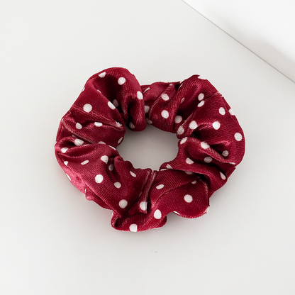 Burgundy scrunchie with white polka dots from Coconut Lane on a white surface. Fabric appears soft.