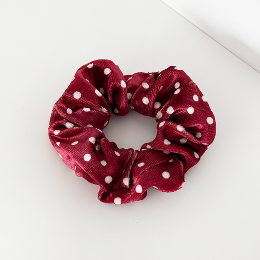Burgundy scrunchie with white polka dots from Coconut Lane on a white surface. Fabric appears soft.