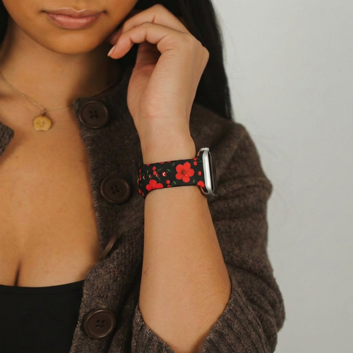 Woman in a brown sweater wearing a Coconut Lane Cherry Hibiscus Apple Watch strap with a floral pattern.