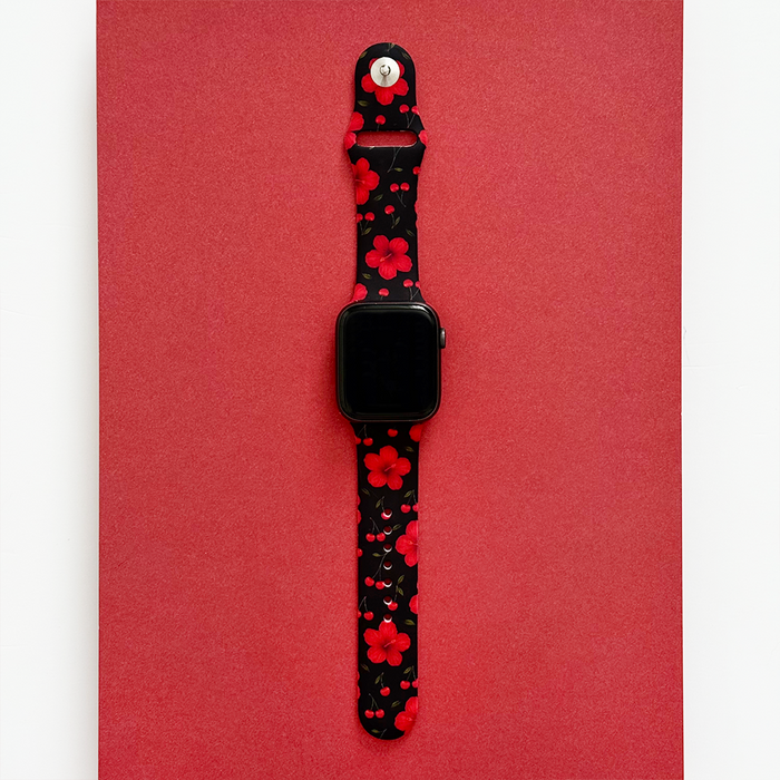 Cherry Hibiscus Apple Watch strap with red flowers on black, displayed on a bold red background.