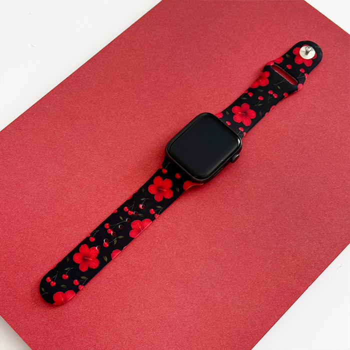 Coconut Lane Apple Watch strap with red cherry hibiscus flower pattern on a red textured background.