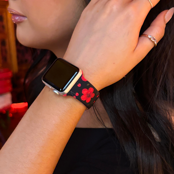 Coconut Lane Cherry Hibiscus Apple Watch strap with red floral pattern on wrist, hand raised near hair.