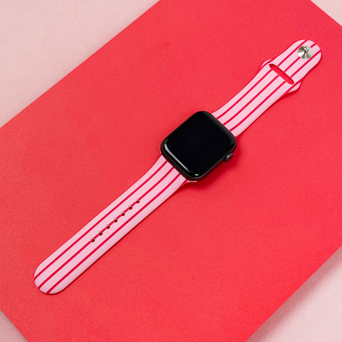 Coconut Lane Apple Watch strap with cherry stripes pattern on a bright pink background.