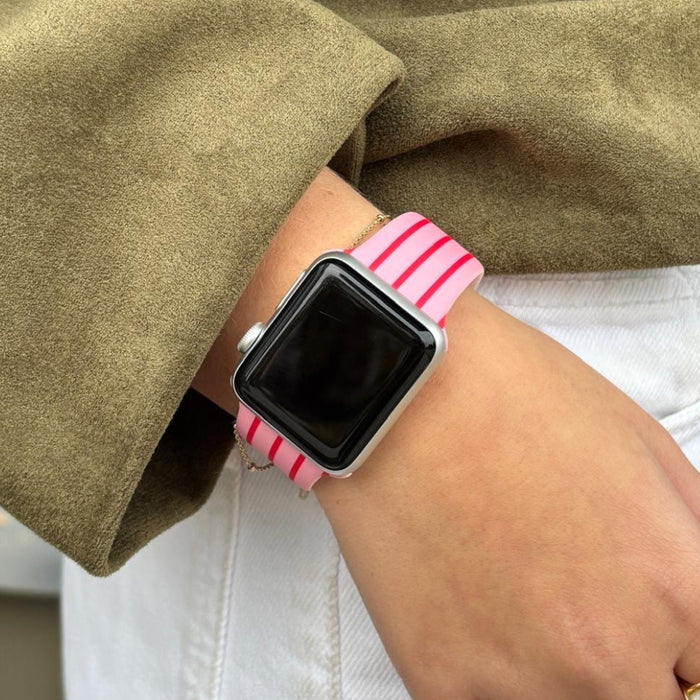 Pink and white striped silicone Apple Watch strap worn on a wrist.