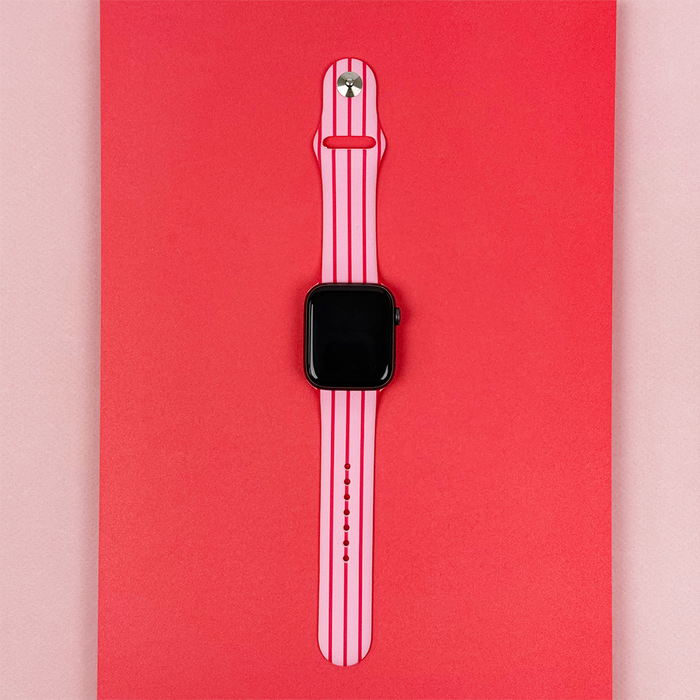 Cherry Stripes Apple Watch strap with red and pink stripes by Coconut Lane, shown on a two-tone red and light pink background.