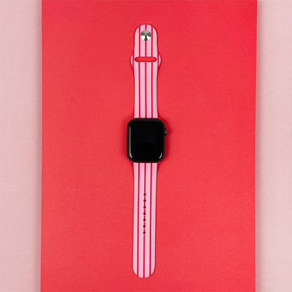 Cherry Stripes Apple Watch strap with red and pink stripes by Coconut Lane, shown on a two-tone red and light pink background.