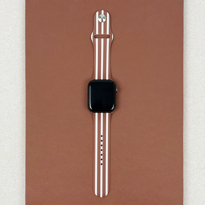 Coconut Lane Apple Watch strap with chestnut brown stripes, displayed on a brown background.