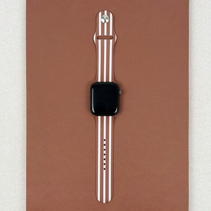 Coconut Lane Apple Watch strap with chestnut brown stripes, displayed on a brown background.