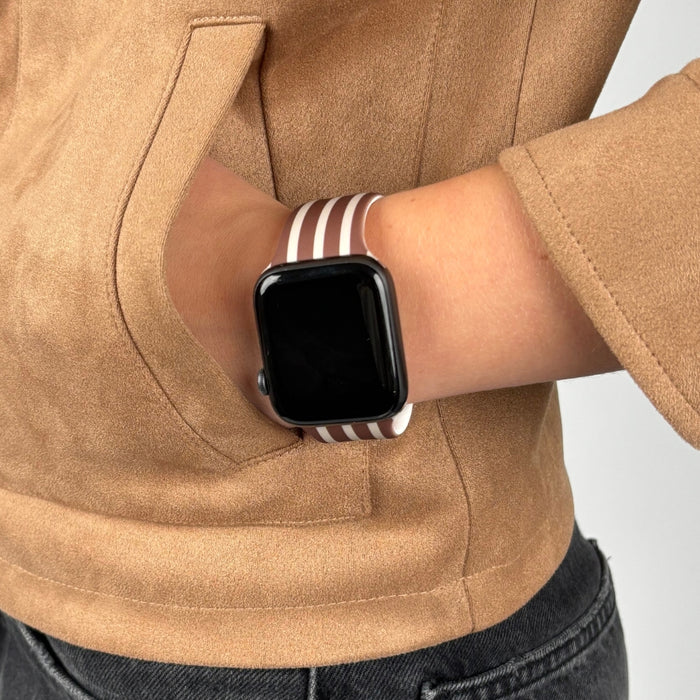 Coconut Lane Chestnut Stripes Apple Watch strap on wrist, paired with a tan jacket, hand in pocket.
