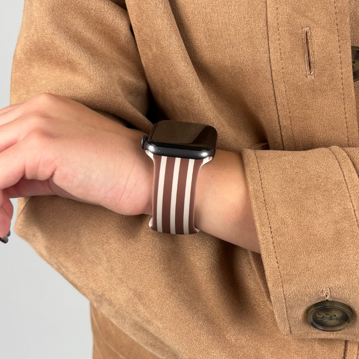 Chestnut striped Apple Watch strap on wrist, worn with a tan coat.