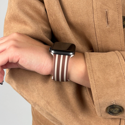 Chestnut striped Apple Watch strap on wrist, worn with a tan coat.