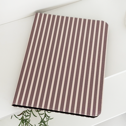 Chestnut Stripes iPad case in vegan leather on a white surface next to a green plant.
