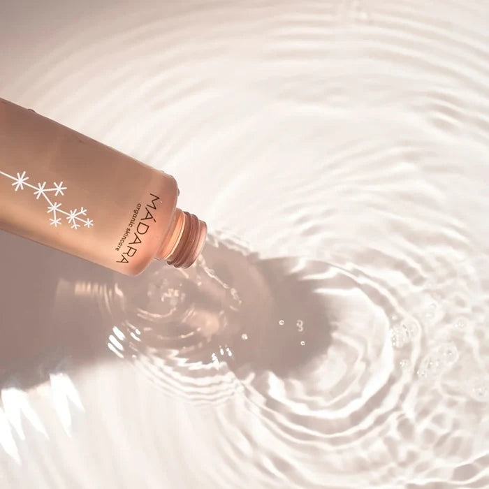 Rose gold bottle with Madara branding on water surface.
