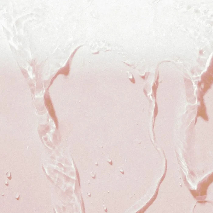 Close-up of clear liquid on a pink background.