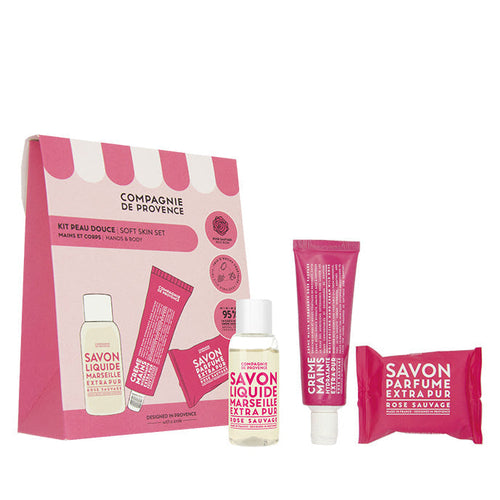 A gift set by Compagnie de Provence including a liquid soap, a moisturizing hand cream, and a perfumed soap, all with a rose fragrance, packaged in a pink box.