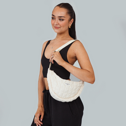 Woman in black holds a light grey Crescent Dog Walking Bag Bundle by Coconut Lane, smiling against a pale background.