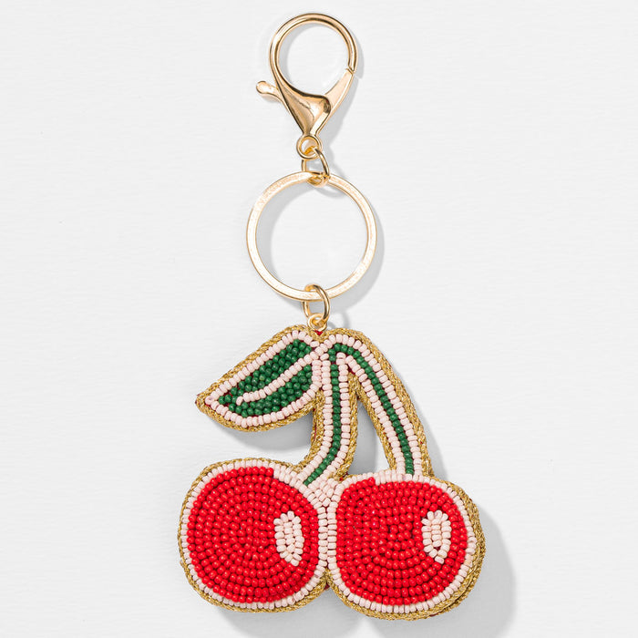 Cherry bead bag charm with red, green and white accents, adding a playful touch to everyday bags
