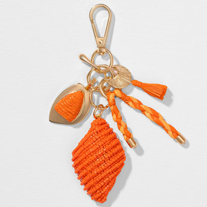 Orange raffia tassel bag charm with beadwork, bringing beachy elegance to everyday bags