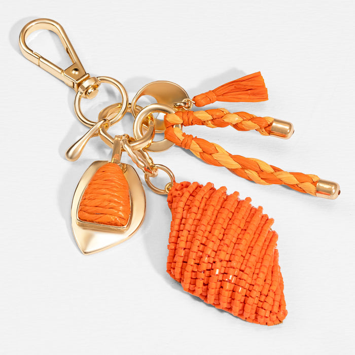 Handcrafted orange bag charm with raffia tassels and beads for a chic coastal-inspired look