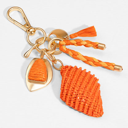 Handcrafted orange bag charm with raffia tassels and beads for a chic coastal-inspired look
