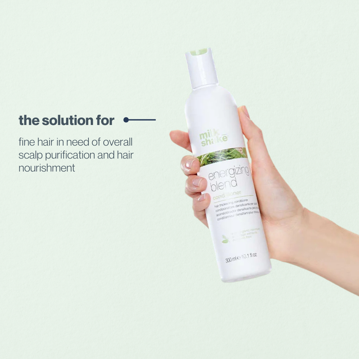 Hand holding a bottle of 'milk_shake' energizing blend product against a light green background