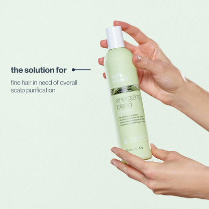 Hand holding a bottle of 'milk_shake energizing blend' product with text on a light background