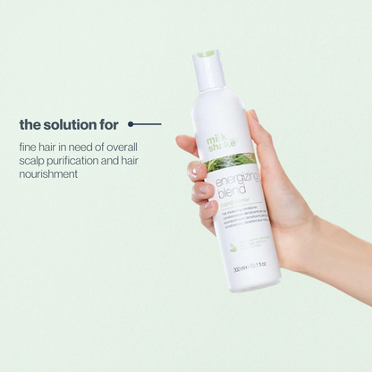 Hand holding a bottle of 'milk_shake' energizing blend product against a light green background