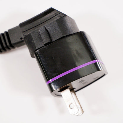 Close-up of a black travel plug adapter with a purple band, two metal prongs, and an attached black cord on a white background.