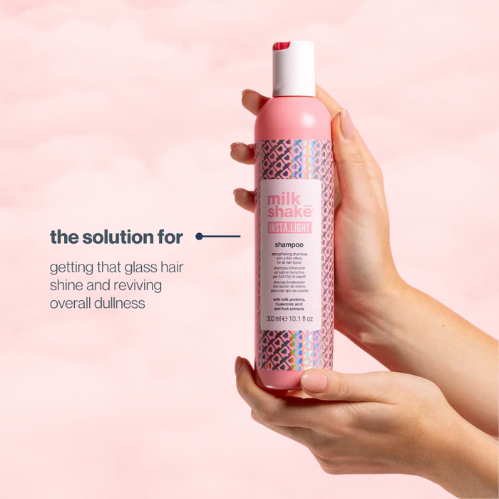 Hand holding a pink milk_shake INSTA.LIGHT shampoo bottle with text on a pink background
