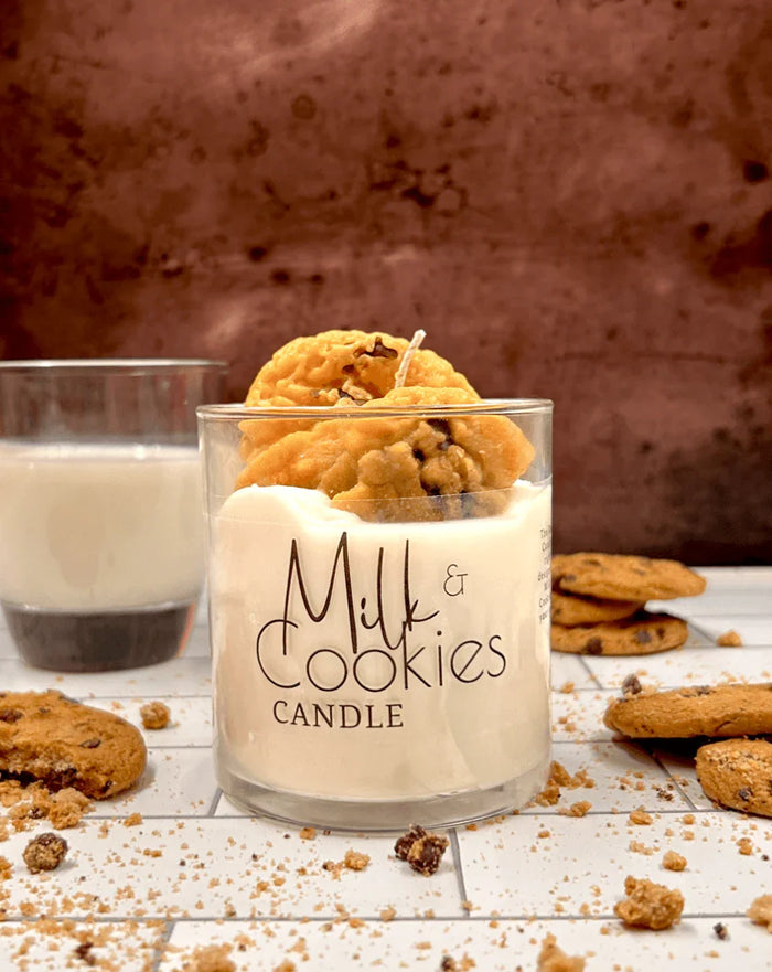 Milk and cookies dessert candle in a glass, surrounded by chocolate chip cookies and milk.