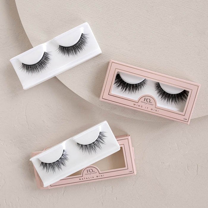 Three pairs of false eyelashes in pale pink and white boxes with clear windows