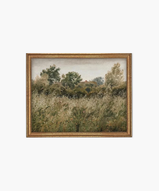 A framed landscape painting depicts a serene meadow with tall, lush grass and distant trees under a cloudy sky. The scene evokes tranquility. | Wildwood Home Co.