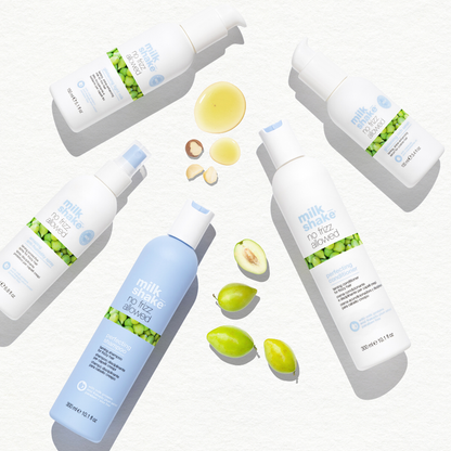Multiple bottles of milk_shake no frizz allowed products on a white background with green and blue elements.