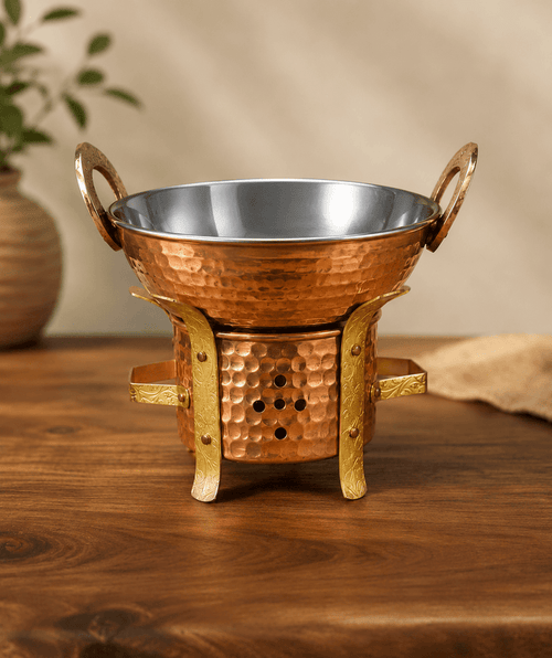 Copper oil warmer with hammered bowl, small legs, and side handles with metal rim