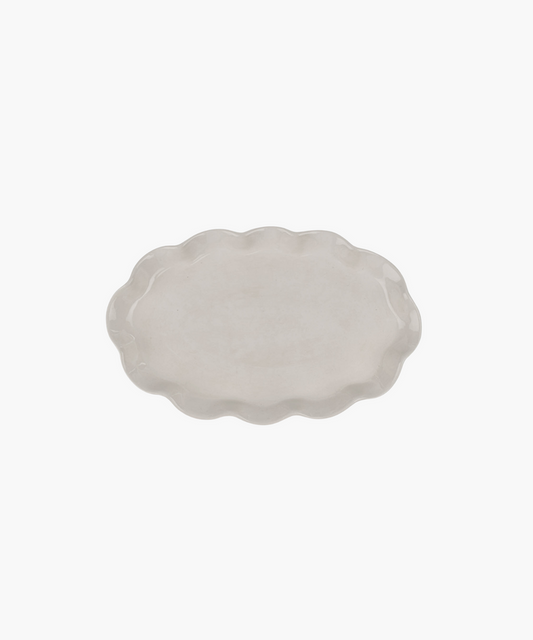 An oval, ceramic platter with a wavy, scalloped edge in a light cream color. The minimalist design conveys simplicity and elegance. | Wildwood Home Co.