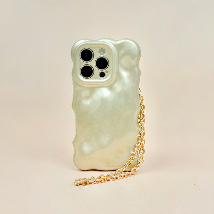 Gold chain phone strap by Coconut Lane attached to a pearlescent wavy case on a light beige surface.