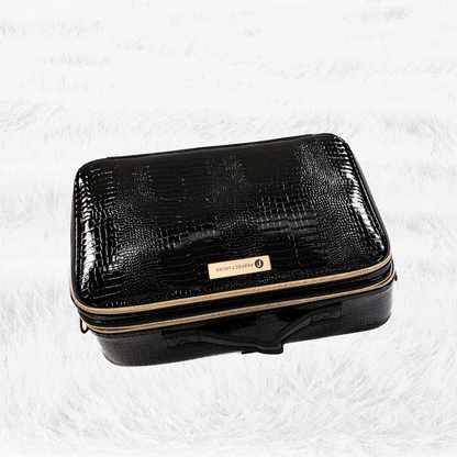 A black textured rectangular suitcase with a zipper and nameplate on top rests on a white fluffy surface, adding an elegant touch.