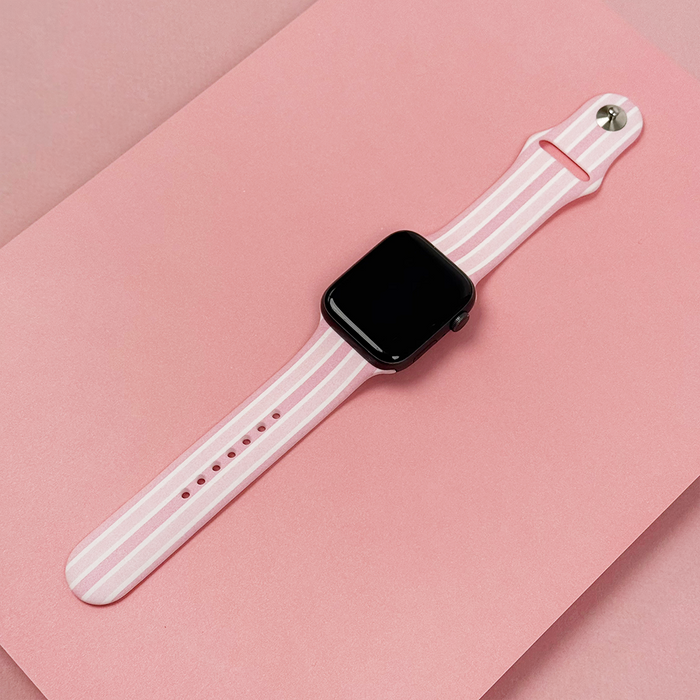Coconut Lane Powder Stripes Apple Watch strap with pastel stripe pattern on a pink background.