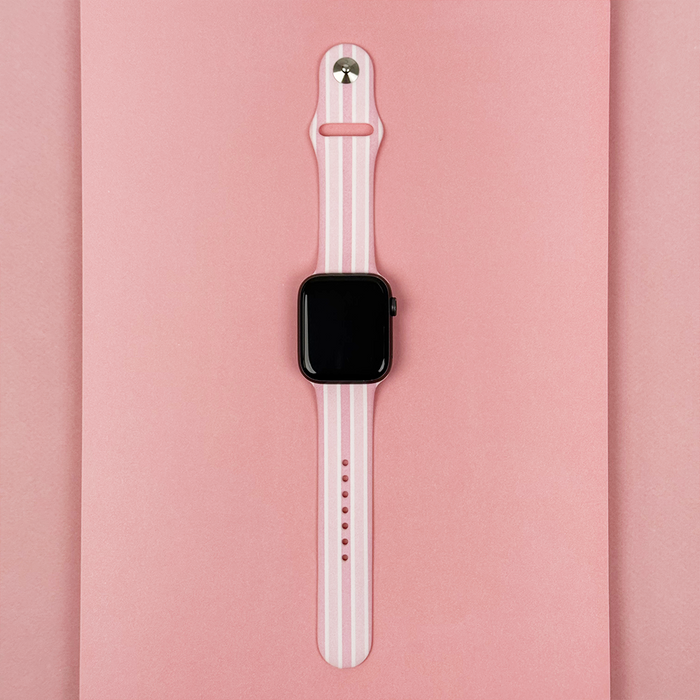 Coconut Lane Apple Watch strap with powder stripes pattern on a pink background.