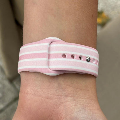 Pink and white striped Coconut Lane Apple Watch strap shown on a wrist.