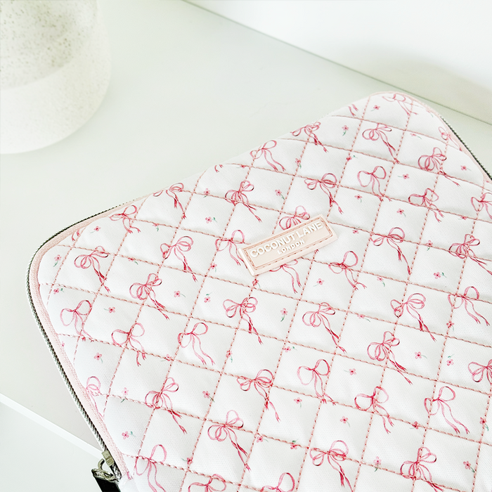 Quilted iPad sleeve with pink and white panels and small bows on a soft white surface.
