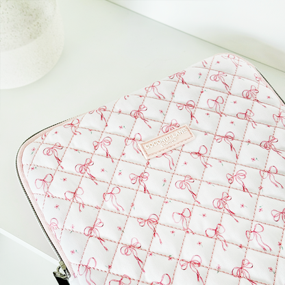 Quilted iPad sleeve with pink and white panels and small bows on a soft white surface.