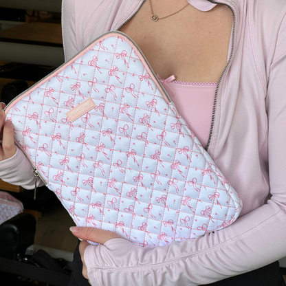 Person in pink top holding a quilted iPad sleeve with a dainty bows pattern and zip closure.
